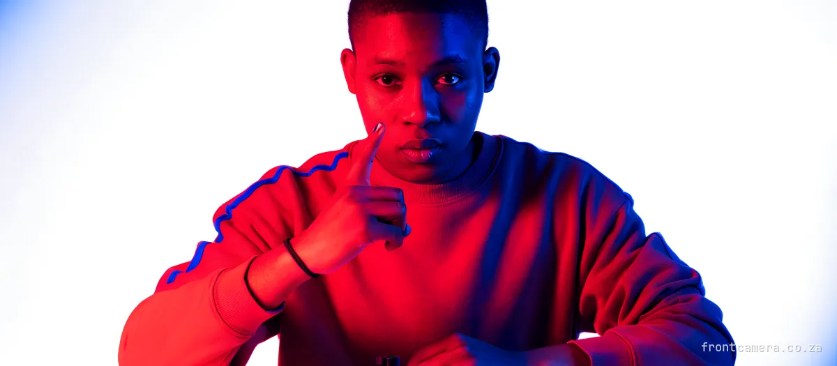 A young South African creator at a kitchen table laying out a phone, a small tripod, a clip-on microphone and a ring light in a neat row, counting on their fingers